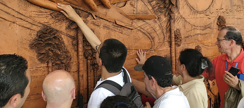 Fotografía, personas con discapacidad visual tocando un cuadro en relieve