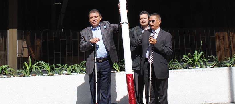 funcionarios sosteniendo un bastón blanco gigante