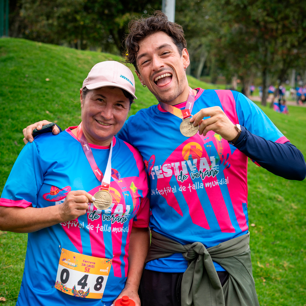 Dos participantes sonríen y muestran sus medallas después de completar la carrera 5K Sin Límites.