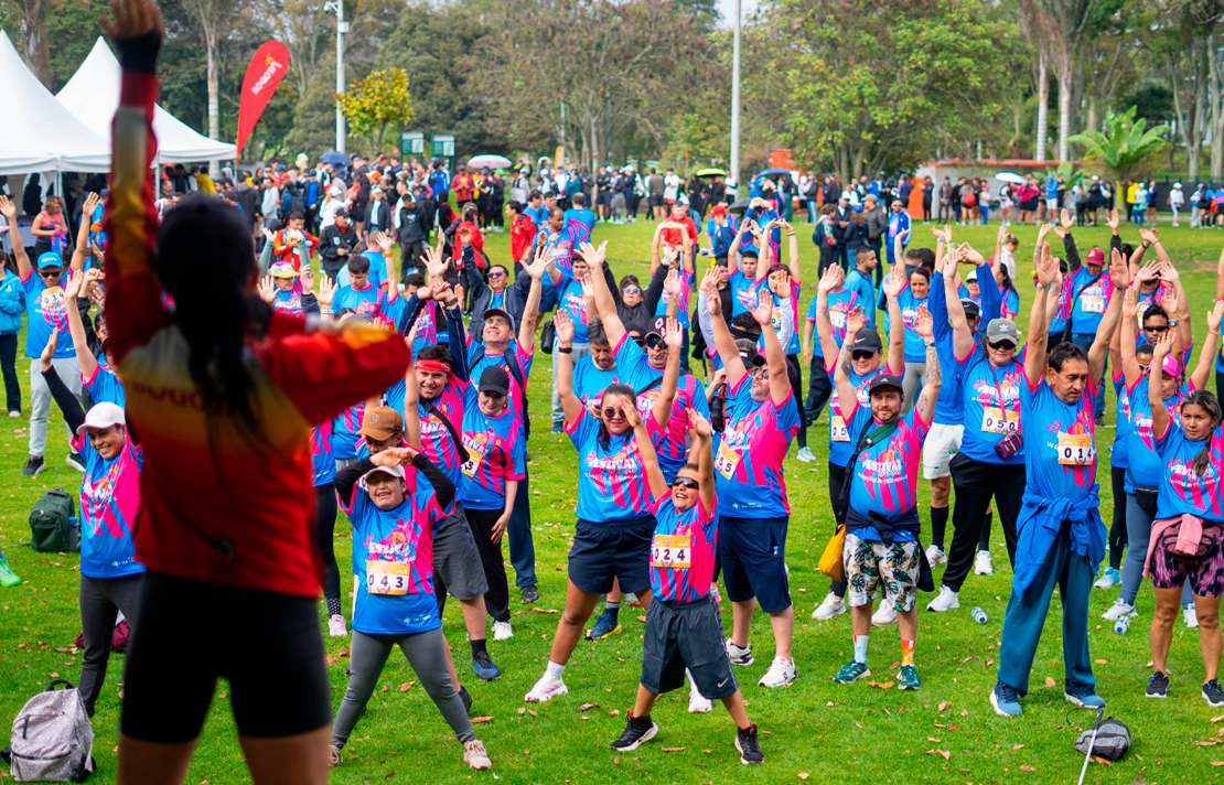 Participantes de la carrera 5K Sin Límites realizan una jornada de calentamiento grupal antes de iniciar el recorrido, en el marco del Festival de Verano de Bogotá.