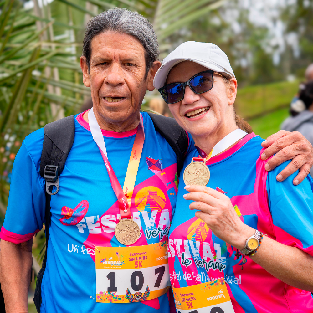 Dos participantes con discapacidad visual posan abrazados y muestran sus medallas al finalizar la carrera 5K Sin Límites.
