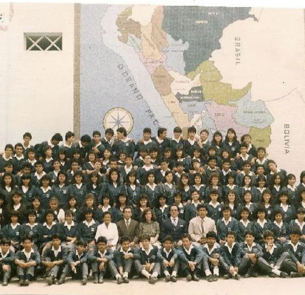 frente a un mapa de suramerica que está en un gran muro, está un gran grupo de alumnos y docentes