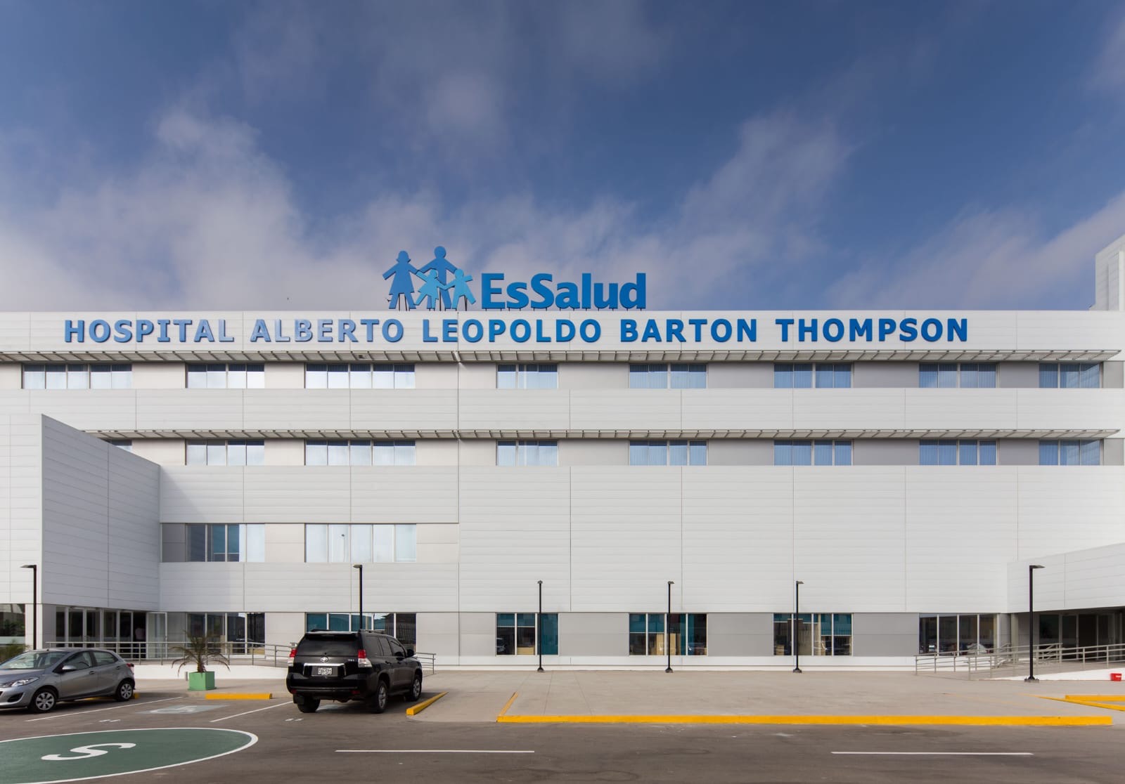 Hospital Alberto Leopoldo Barton Thompson, el edificio es blanco el texto del nombre está en azul y en la parte superior hay una imagen de una mujer y un hombre junto a dos niños a la derecha hay un letrero en ezul que dice EsSalud