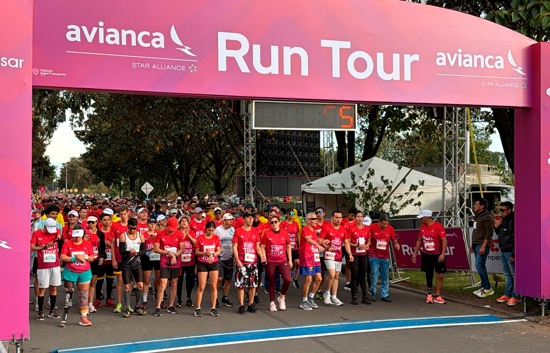 Grupo de participantes con discapacidad visual, acompañantes y miembros del equipo organizador posan con sus medallas después de completar el Run Tour Avianca 2026 en Bogotá.