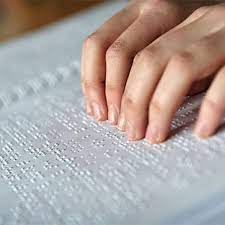 imagen unas manos pasan sobre un texto en braille