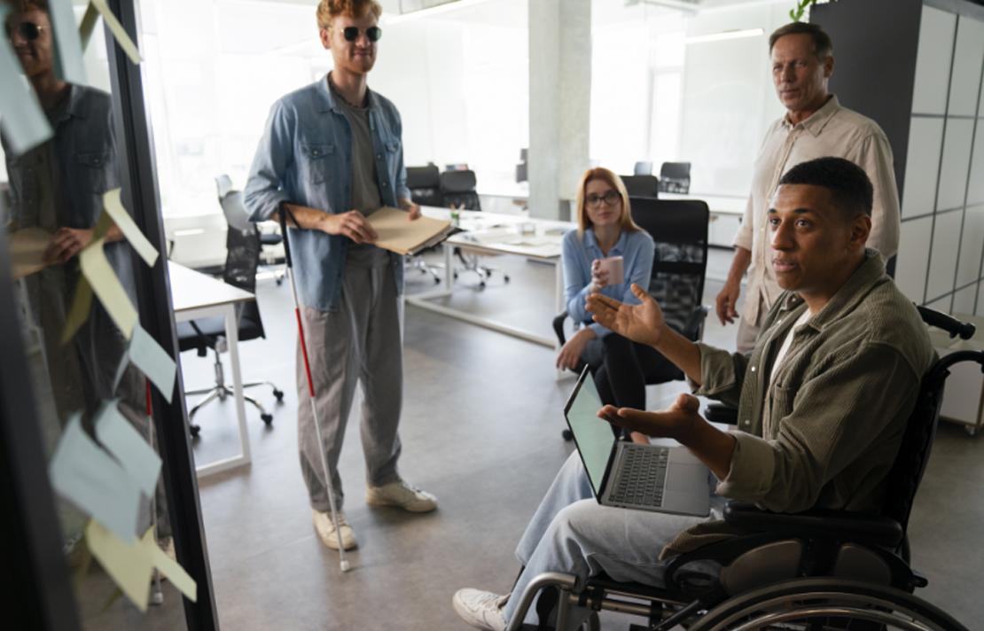 Varias personas con discapacidades, entre ellas un hombre ciego, trabajando en su trabajo de oficina