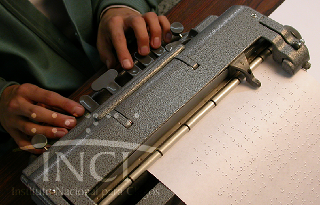 manos de un hombreutilizando en una maquina de escribir en braille
