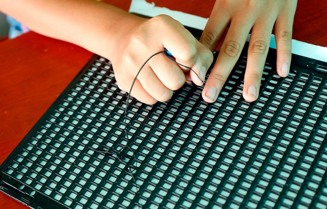 Fotografía persona usando un punzon y una regleta