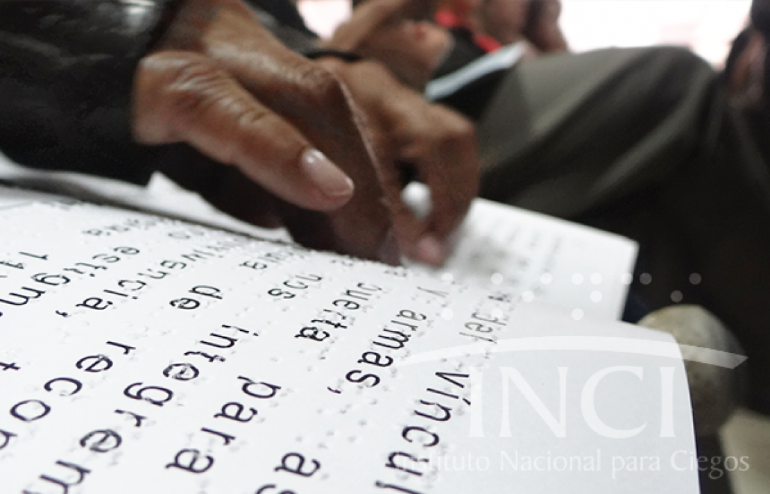 primer plano de las manos de una persona palpando un texto en braille