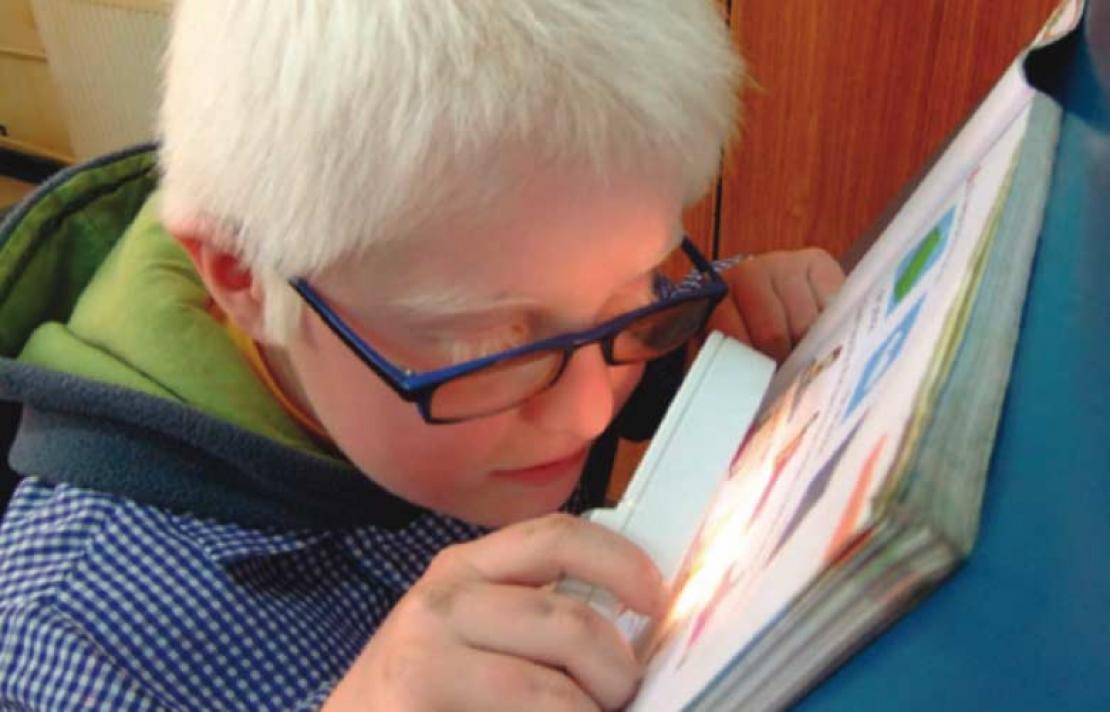 Niño con Baja visión interactuando con un libro