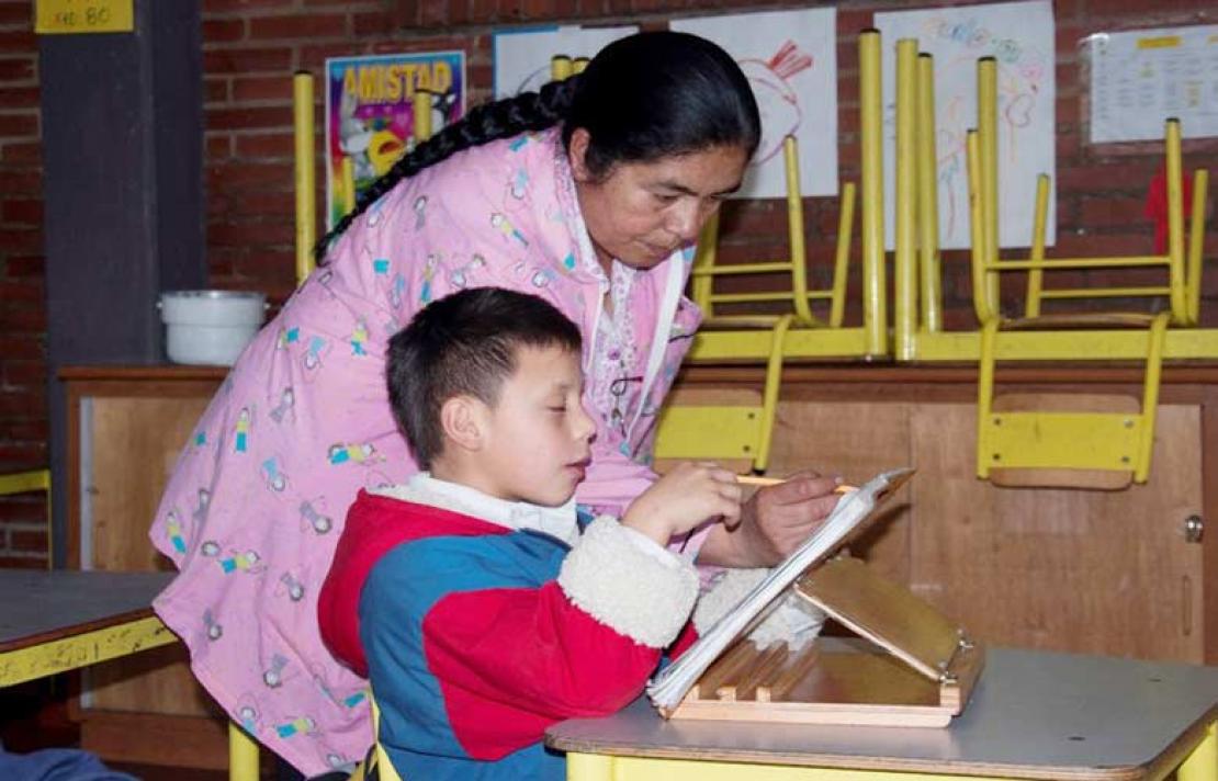 Profesora junto con un niño con discapacidad