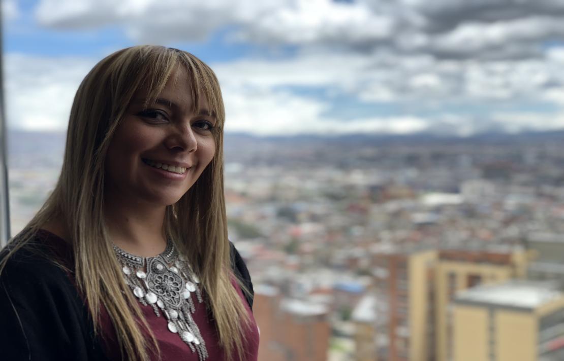 Adriana Pardo Imagen Adriana en primer plano sonríe, de fondo se ve Bogotá, imagen tomada en el piso 30 del hotel Tequendama