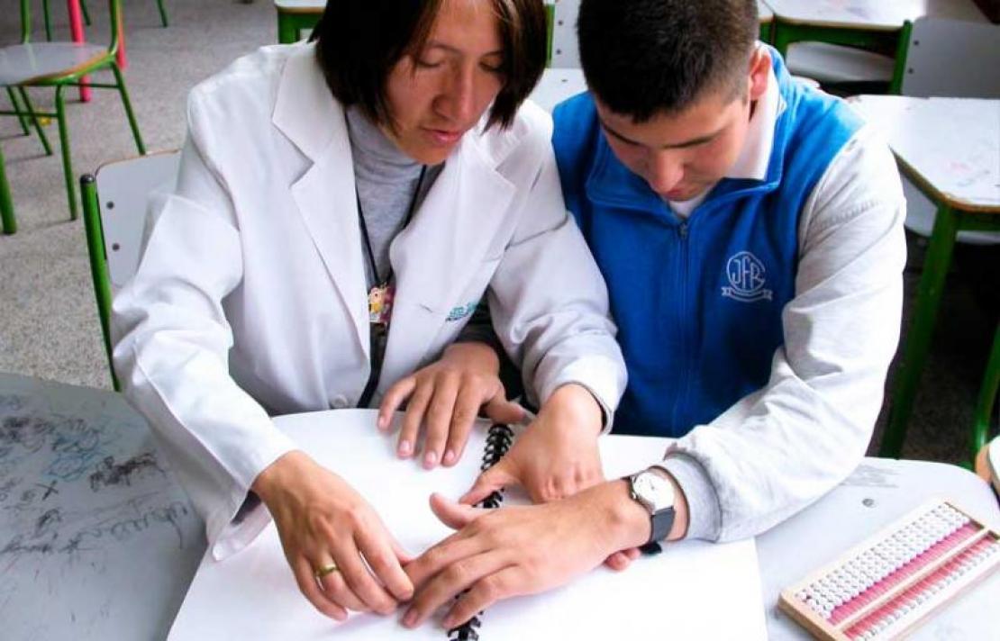 Profesora enseñando braille a niño ciego