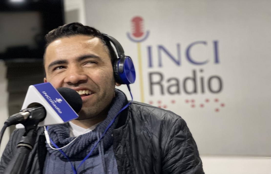 Carlos Quintero en la cabina de INCIRadio, él sonríe frente al micrófono