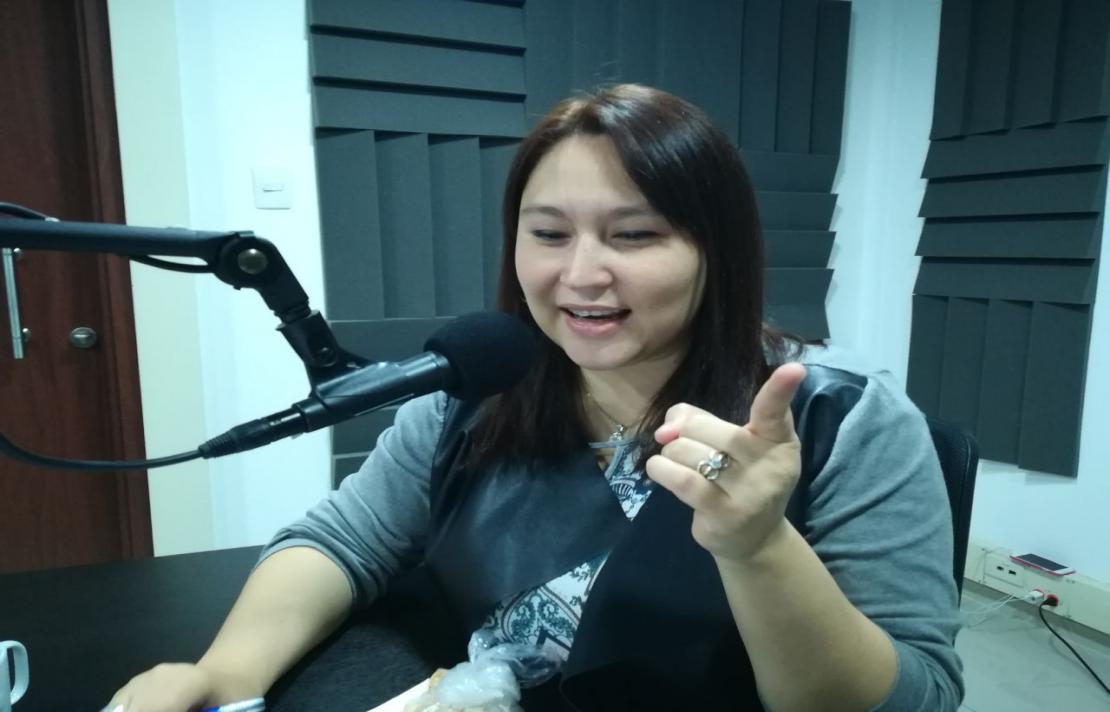Leidy Hoyos imagen de leidy hoyos en la cabina de inciradio, ella lee un texto, está frente al micrófono con su dedo señala hacia al lado
