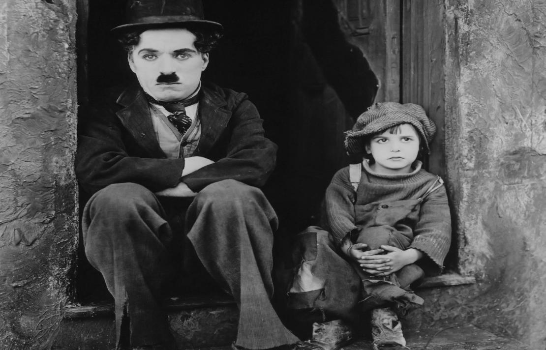 foto de la película de Kid charles Chaplin están sentado junto a Jackie Coogan actor de &quot;The kid&quot;, ellos están sentados frente a una puerta