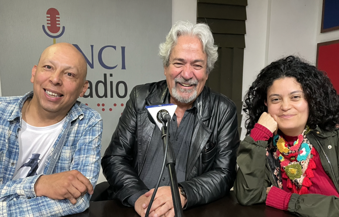 de izquierda a derecha Jota viste una camisa a cuadros, en el centro está Manuel vega quien viste una camisa negra mismo color de su chamarra de cuero, a la derecha está claudia quien viste una chamarra de color verde y una blusa rosada, los tres sonríen, de fondo están los paneles acústicos de la emisora INCIRadio
