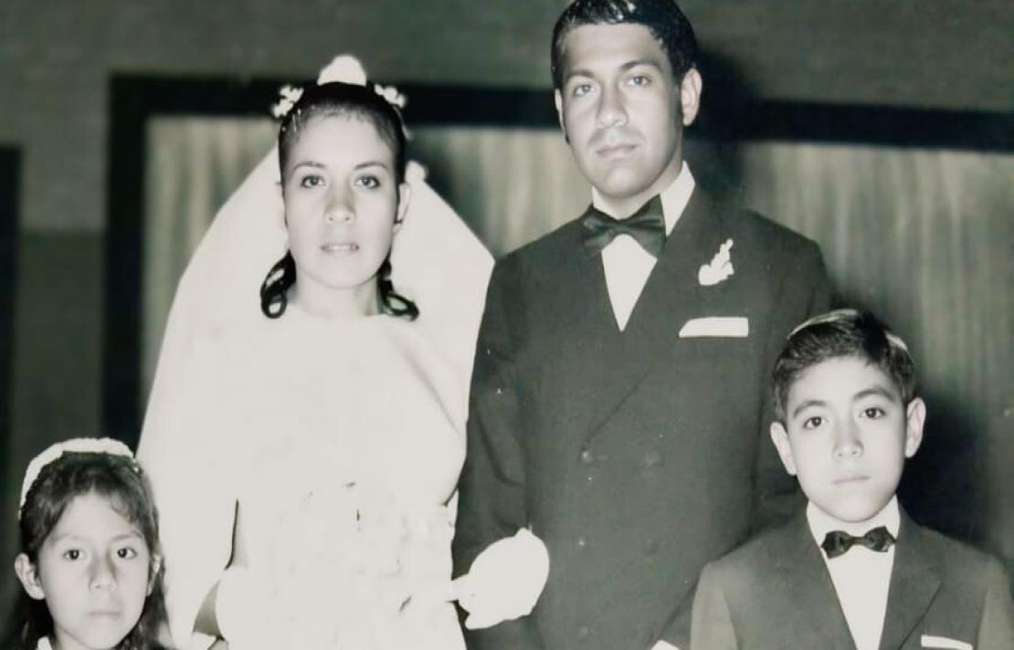 blanco y negro una pareja de esposos junto a un niño y una niña, el niño y el señor visten un traje oscuro camisa blanca y corbatín, mientras la niña y la esposa visten de blanco