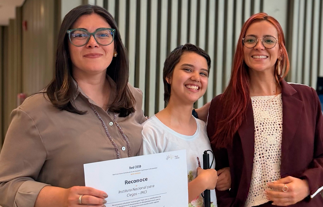 Andrea Carolina Chacón Castillo, directora general del INCI, junto a Sara Muñoz, estudiante del Tecnológico de Antioquia y usuaria de bastón blanco, y otra participante durante una actividad por el Día Mundial del Bastón Blanco. En la imagen se exhibe un reconocimiento otorgado al INCI.