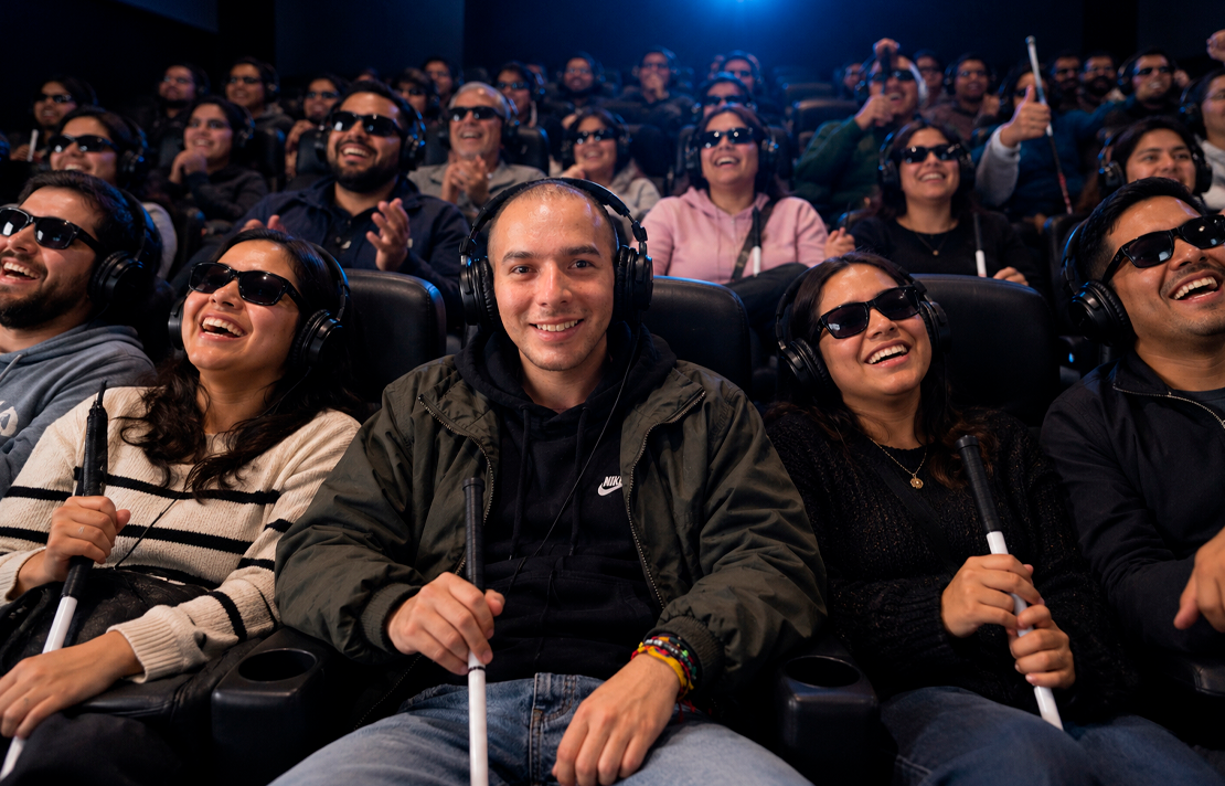 Personas ciegas y con baja visión disfrutan de una proyección cinematográfica con audífonos para audiodescripción y bastones blancos, durante una experiencia de cine accesible en el marco del Festival de Cine para Ciegos del INCI.