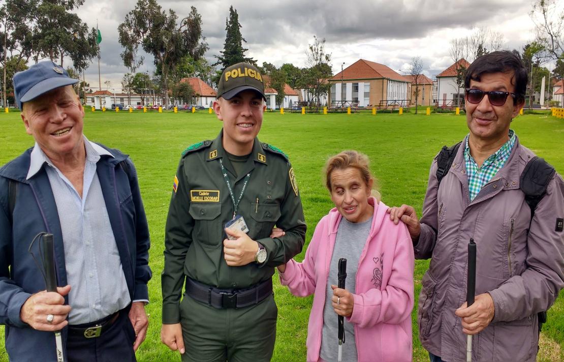 tres personas con discapacidad visual junto a un cadete de la policia