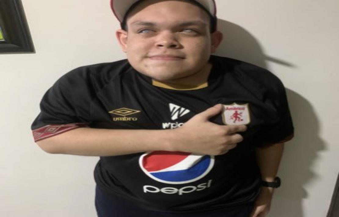 Jhonathan Daza imagen de Jhonathan Daza el sonríe, viste una camisa del América de Cali, su mano está en su pecho sobre el escudo del América,