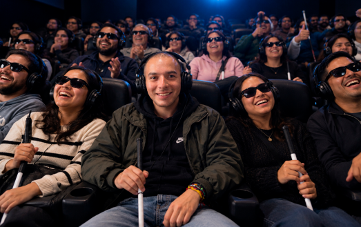 Personas ciegas y con baja visión disfrutan de una proyección cinematográfica con audífonos para audiodescripción y bastones blancos, durante una experiencia de cine accesible en el marco del Festival de Cine para Ciegos del INCI.