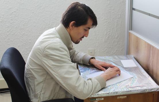 fotografía, persona con discapacidad visual leyendo en braille