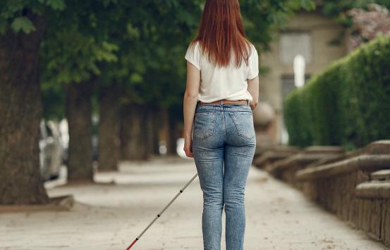 Fotografía - Mujer joven con discapacidad visual camina utilizando bastón