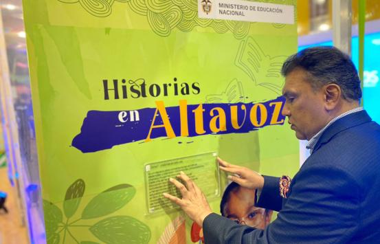 Carlos Parra Dussan presente en el stand del Ministerio de ecuación durante la Filbo 2023, leyendo un texto en braille e