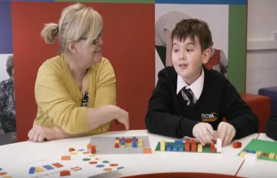 un docente acompaña a un niño con discapacidad visual quien aprovecha unos legos para mejorar su aprendizaje
