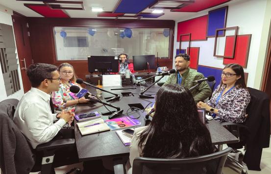 en la cabina de inciradio el equipo de libreta de apuntes está realizando el programa de fondo se ve al productor camilo garnica