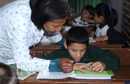 Profesora, enseñandole a un niño CDV a usar la regleta