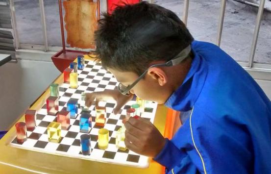 Niño con discapacidad visual jugando con fichas en un tablero