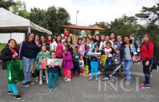 Foto de niños con discapacidad visual y sus familias recibiendo regalos de navidad