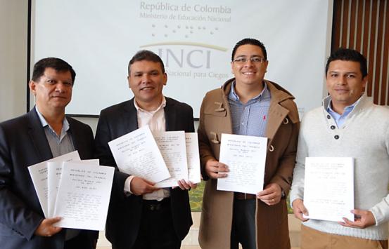 Panelistas evento decretos laborales, sosteniendo los decretos en braille