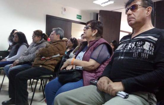 Personas ciegas sentadas escuchando la audiodescripción