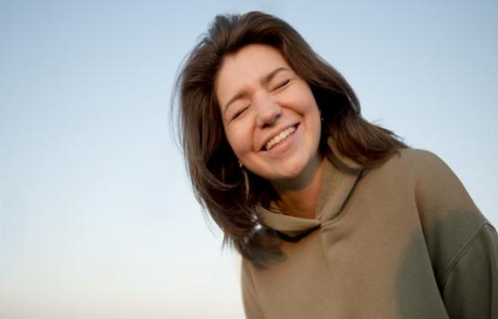 imagen de mujer con baja visión sonriendo de fondo se ve un cielo totalmente azul