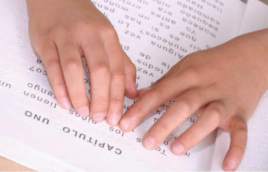 Persona con discapacidad visual, leyendo braille